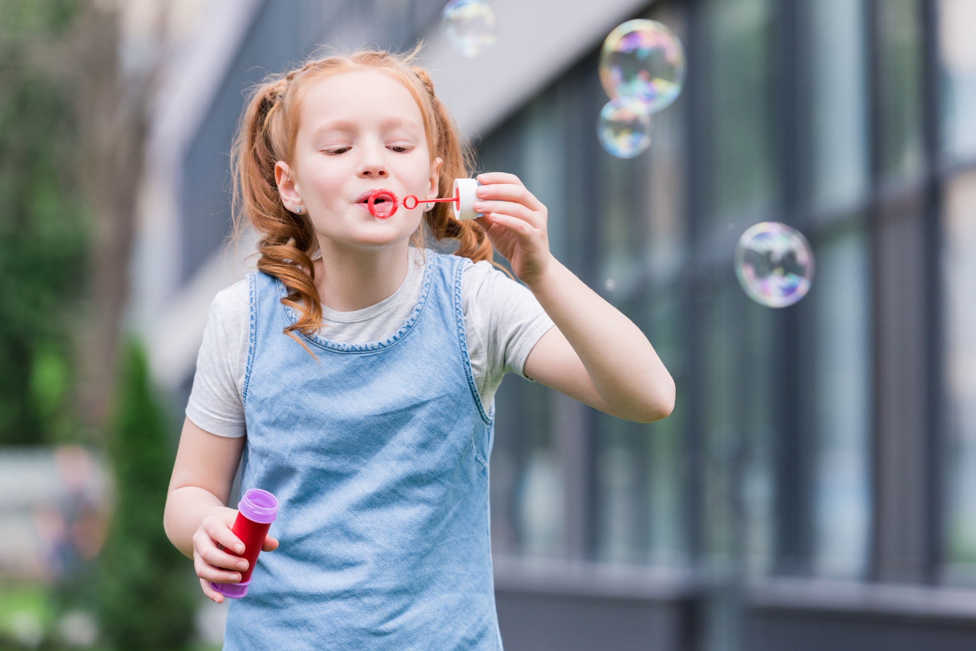 portrait of cute child blowing soap bubbles on street